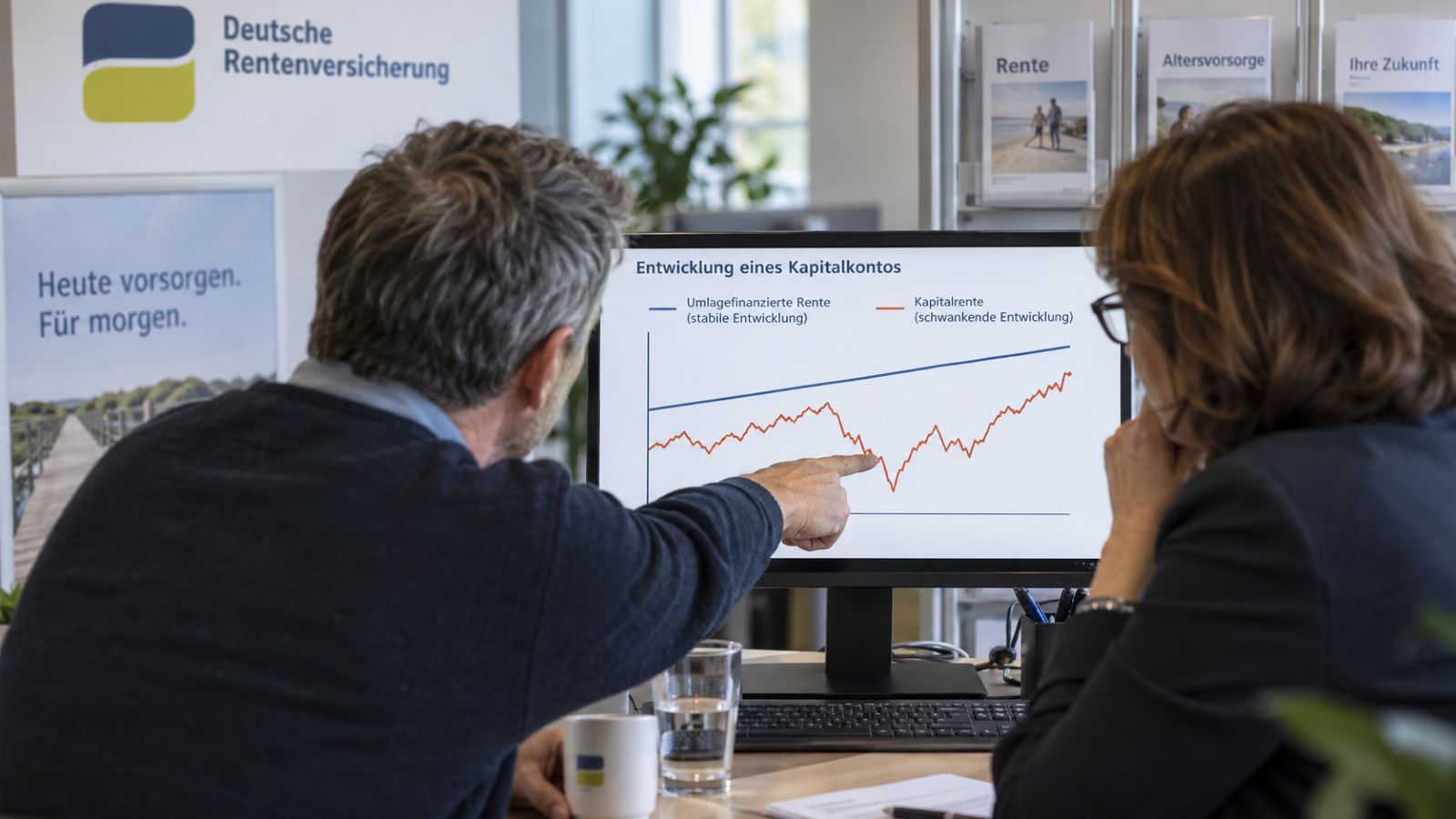 Rentenberaterin zusammen mit Versichertem vergleichen die stabile gesetzliche Rente mit einer schwankenden Kapitalrente am Bildschirm
