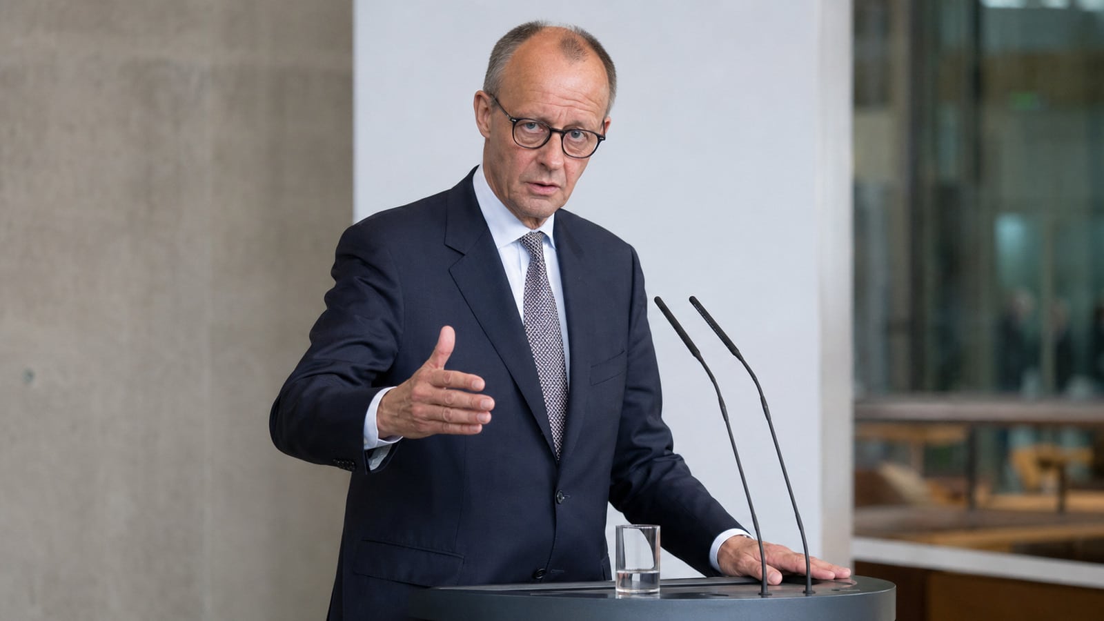 riedrich Merz spricht mit entschlossener Geste an einem Presspult