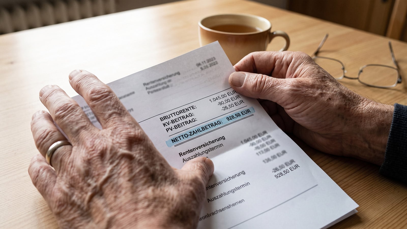 Mann zeigt seinen Rentenbescheid in Nahaufnahme mit Zahlbetrag unter 1.000 Euro