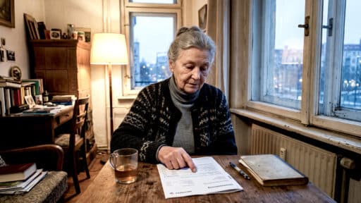 Ärmliche Rentnerin sitzt in ihrer kleinen und alten Wohnung bei einem Glas Tee